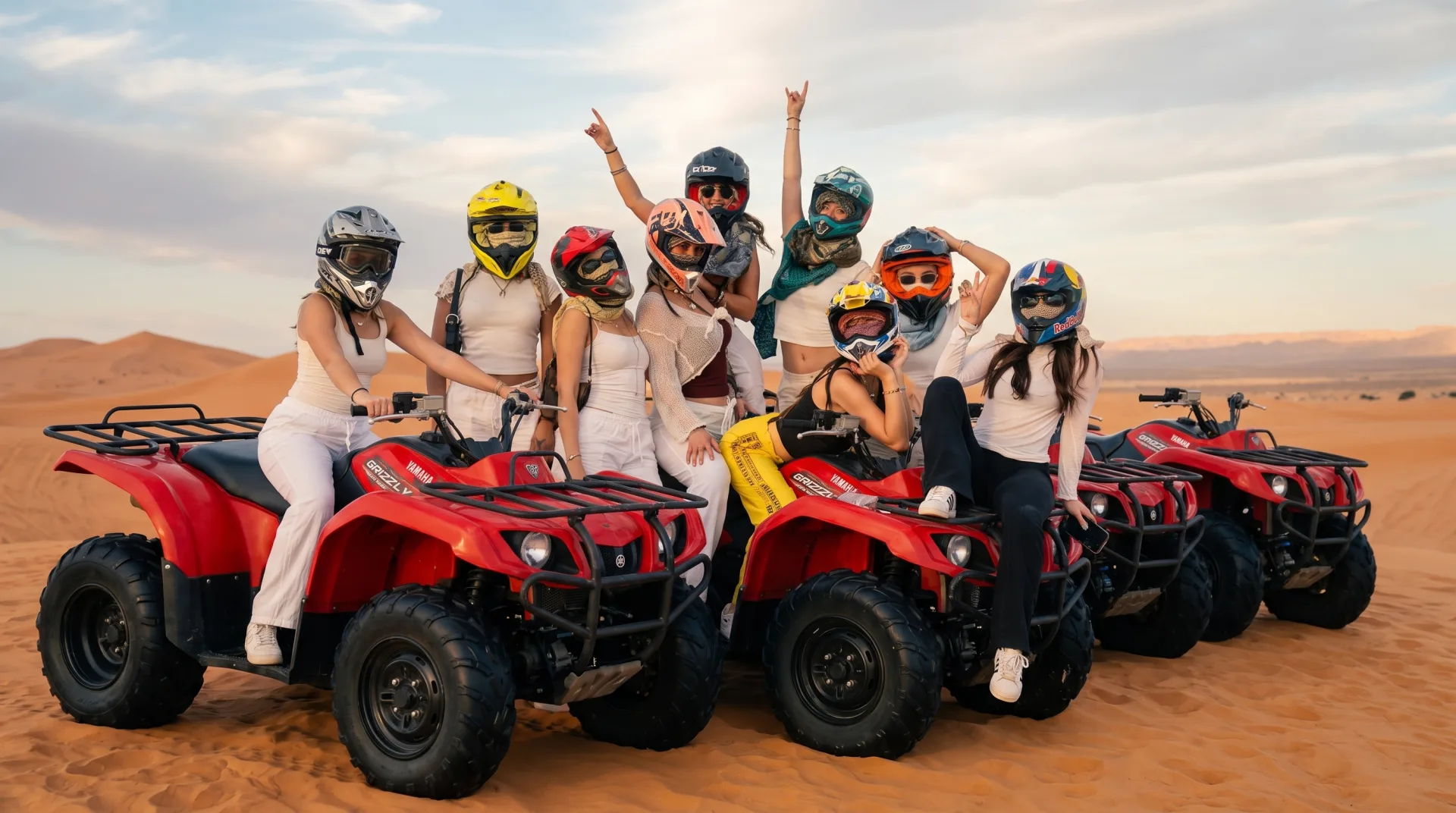A group of riders in helmets on red quad bikes across the Timlaline dunes near Agadir.