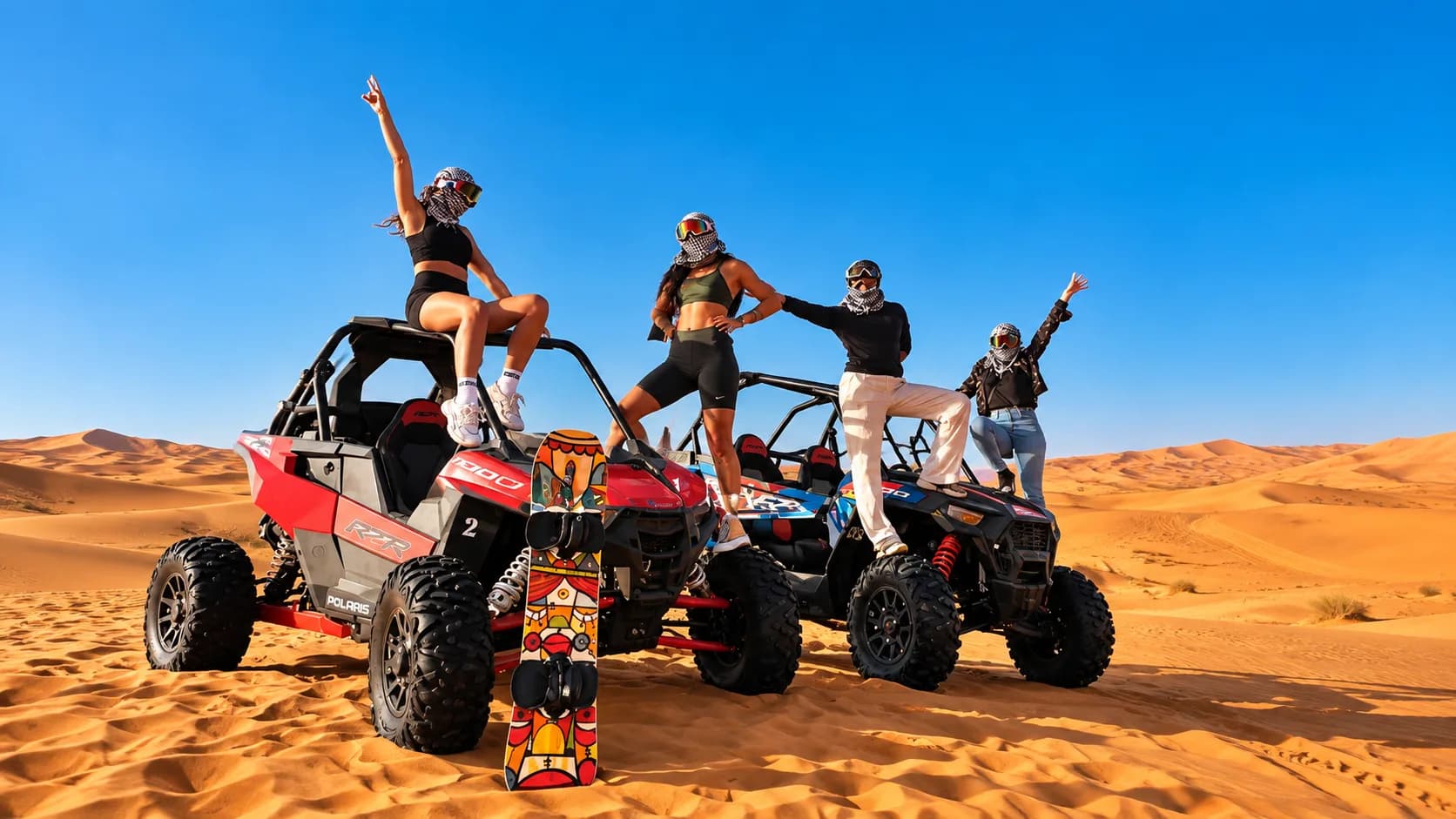 Friends celebrating on top of their buggies in the sand dunes near Agadir